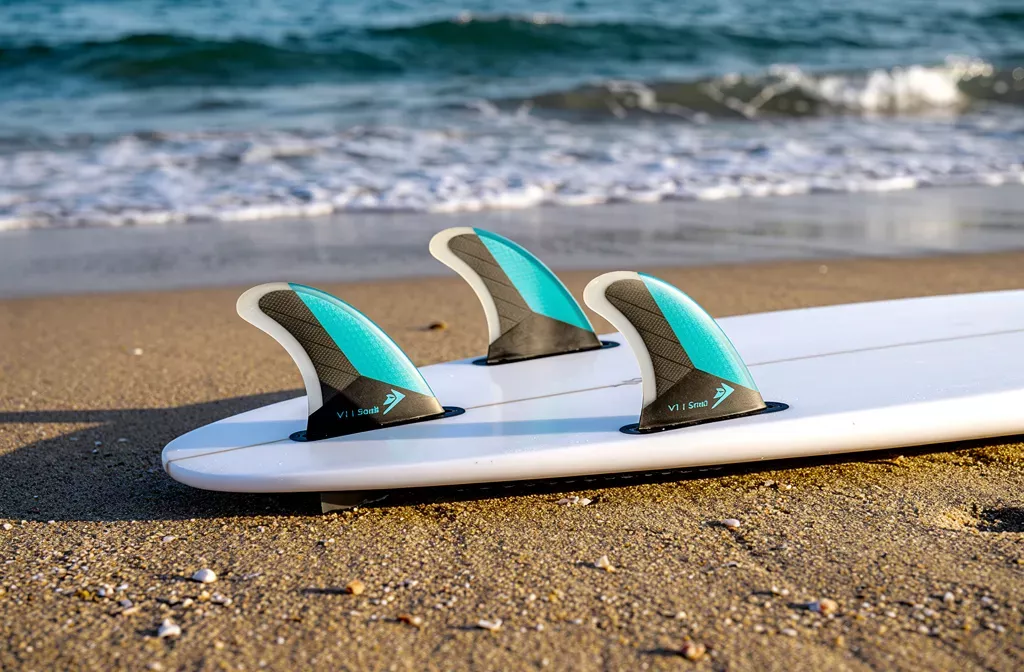 Playa con tabla de surf y aletas traseras turquoise en la orilla. accesorios que usan los surfistas para preparar la tabla.