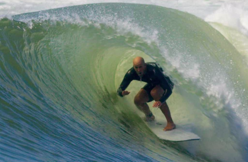 Sfondrato surfista all’interno di una onda tubante, in posizione di piegamento. altezza onde mare.