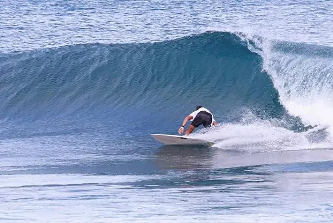 Surfista a rolar numa onda frontal, na posição de carver sobre prancha de surf.