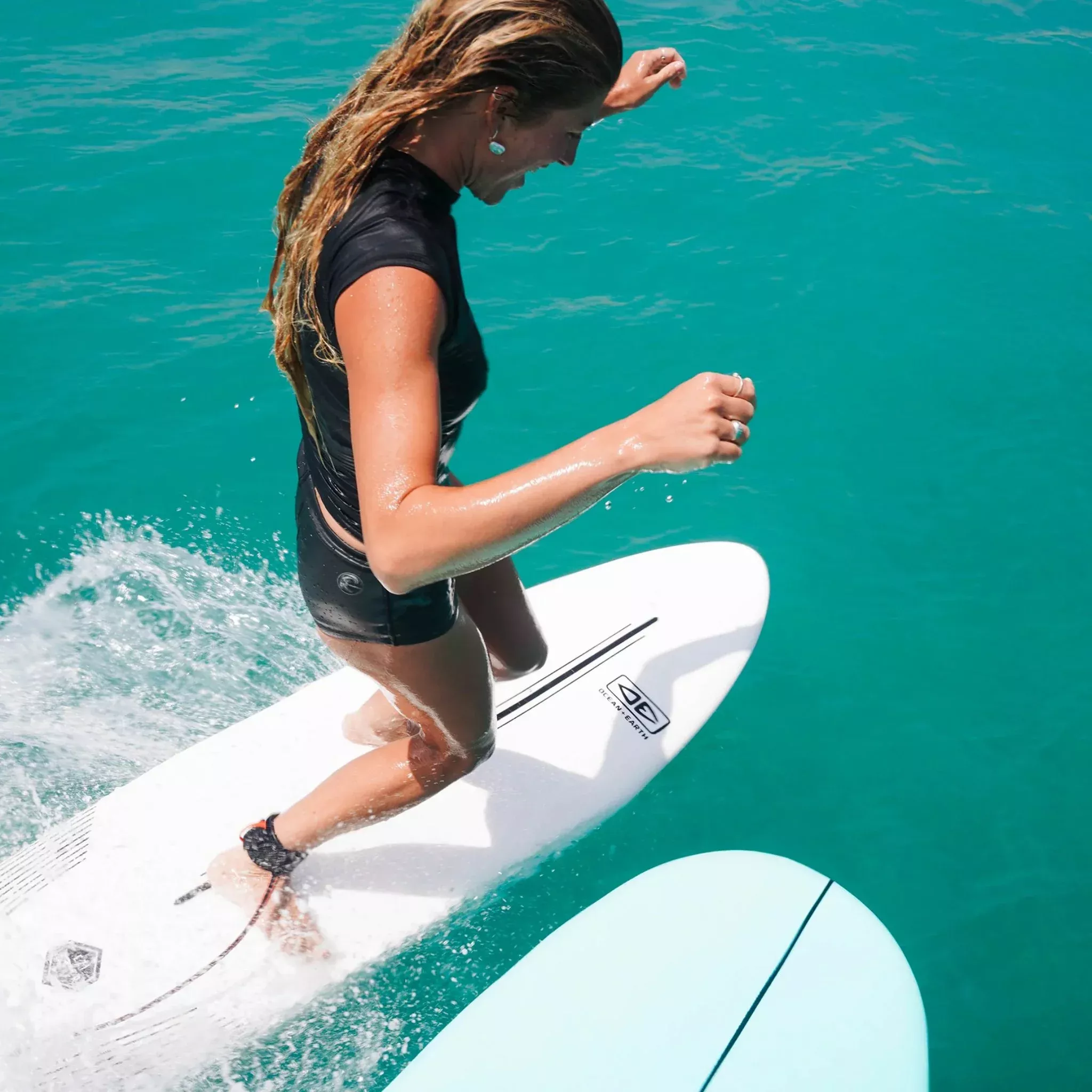 Surfista en tabla corta sobre ola verde, moviéndose hacia la derecha con cuerpo en postura de ride.